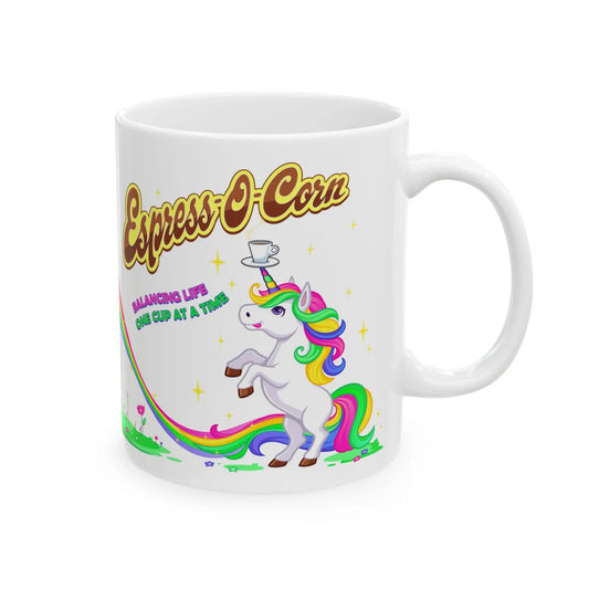 A white ceramic mug with a colorful illustration of a unicorn balancing a cup on its horn, with text reading 'Espress-O-Corn' and a description of the product's function.