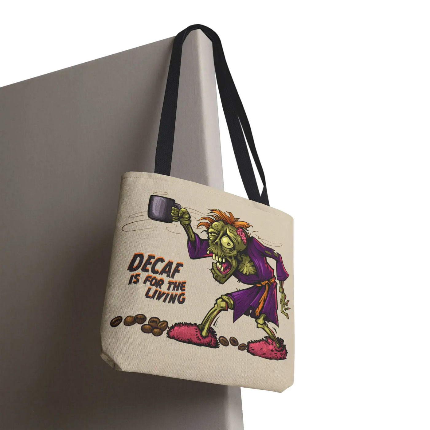 Sand colored tote bag with a funny cartoon zombie holding a mug desperately craving coffee