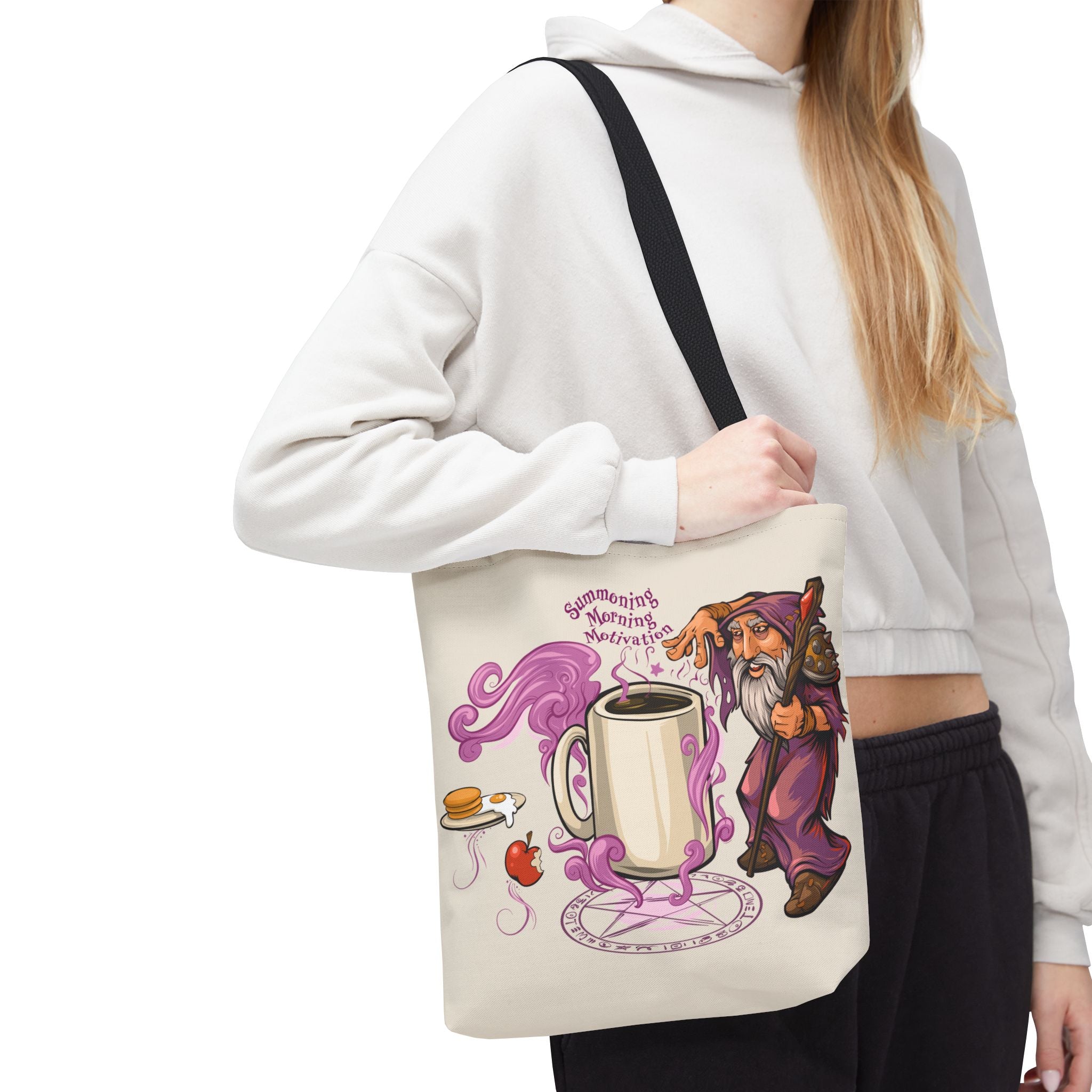 Person holding a tote bag with a cartoon warlock and coffee design.