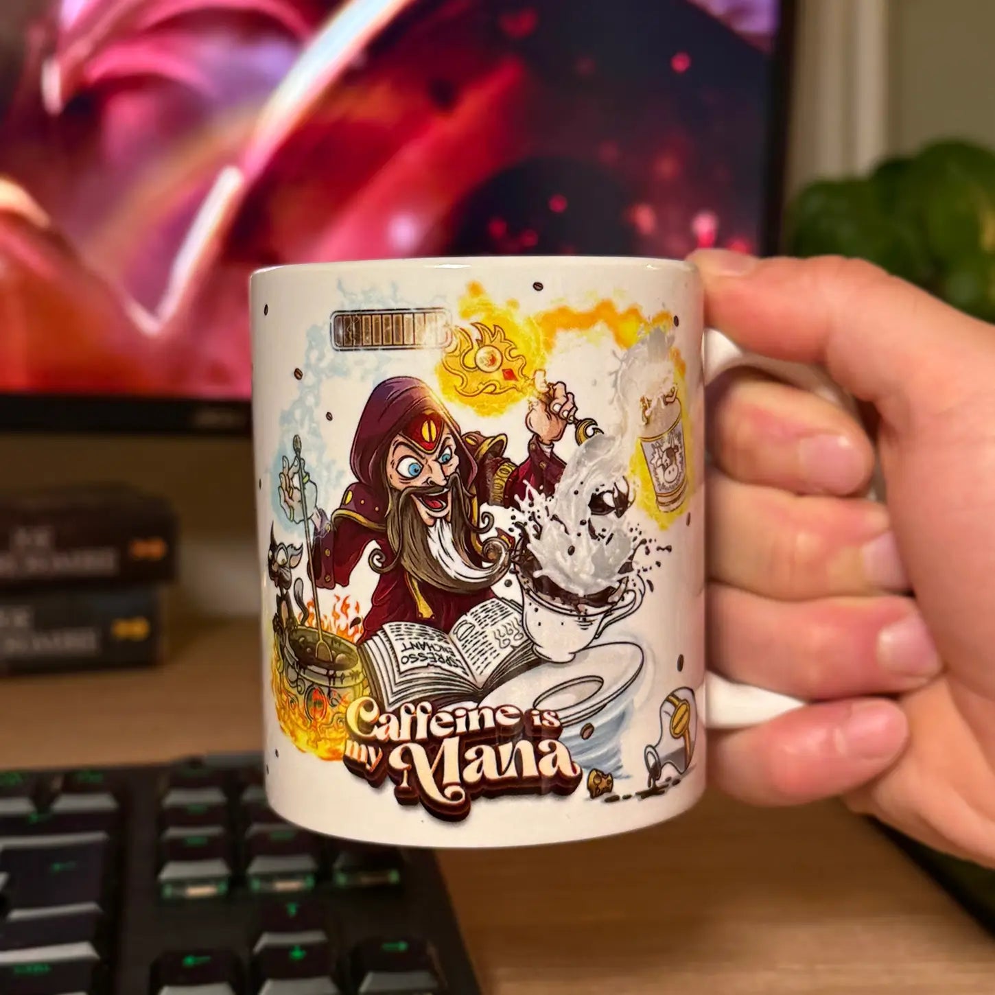 An  11 oz white ceramic fantasy coffee mug held by a hand in front of a computer keyboard and monitor. The mug’s vibrant “Caffeine is my Mana” design shows a cartoon wizard casting spells as coffee erupts from a cup atop an open grimoire, surrounded by glowing potion bottles and a flickering mana bar—perfect as a wizard mug, DnD gift, gamer gift, or fantasy coffee cup.