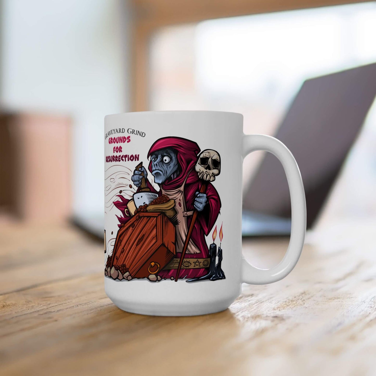 White mug with a colorful graphic of a cartoon necromancer in a robe and hoood on a wooden surface.