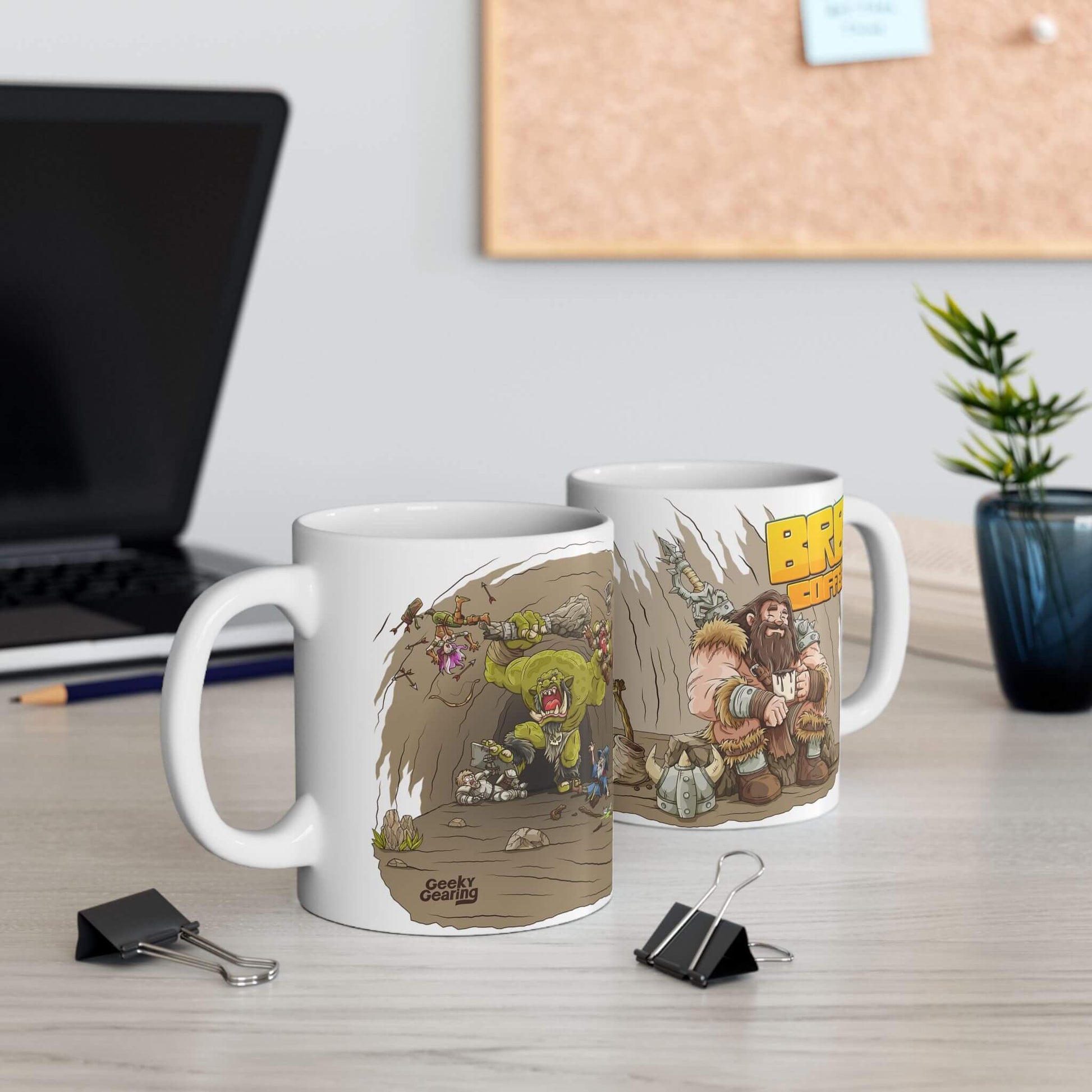 Two mugs with cartoon designs on a desk with office items.