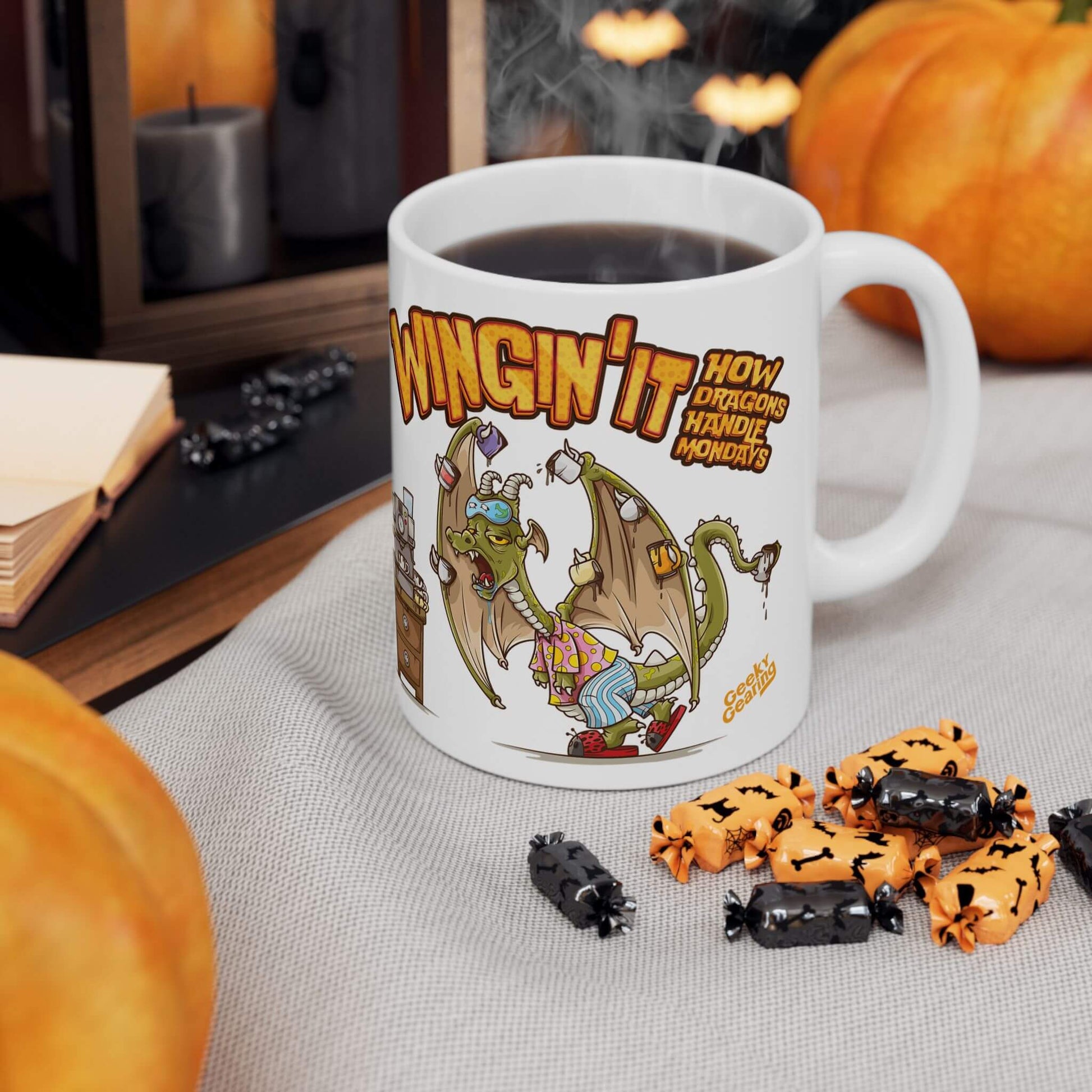Mug with dragon design and text, surrounded by Halloween-themed treats and pumpkins.