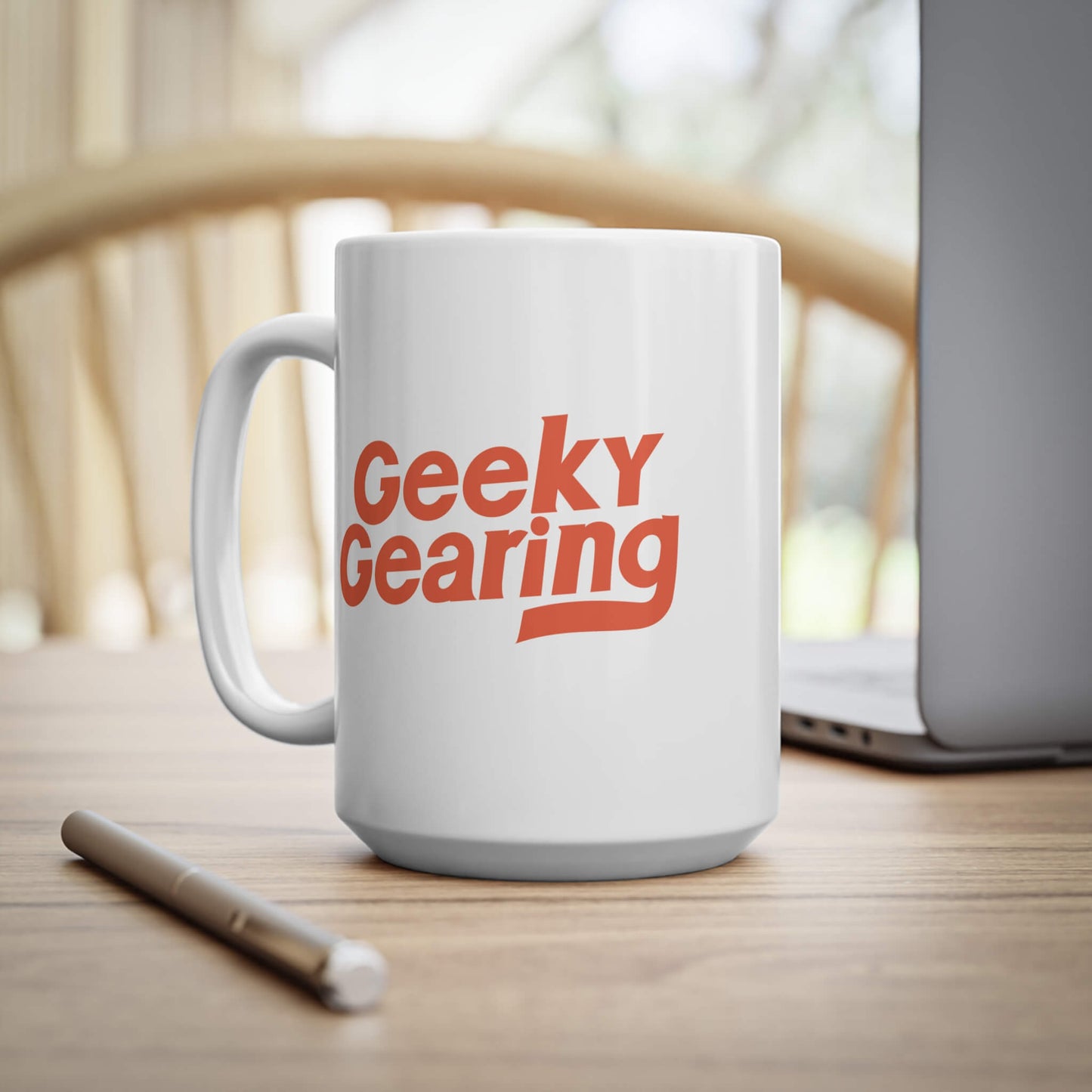 White mug with 'Geeky Gearing' text on a wooden surface with a blurred background