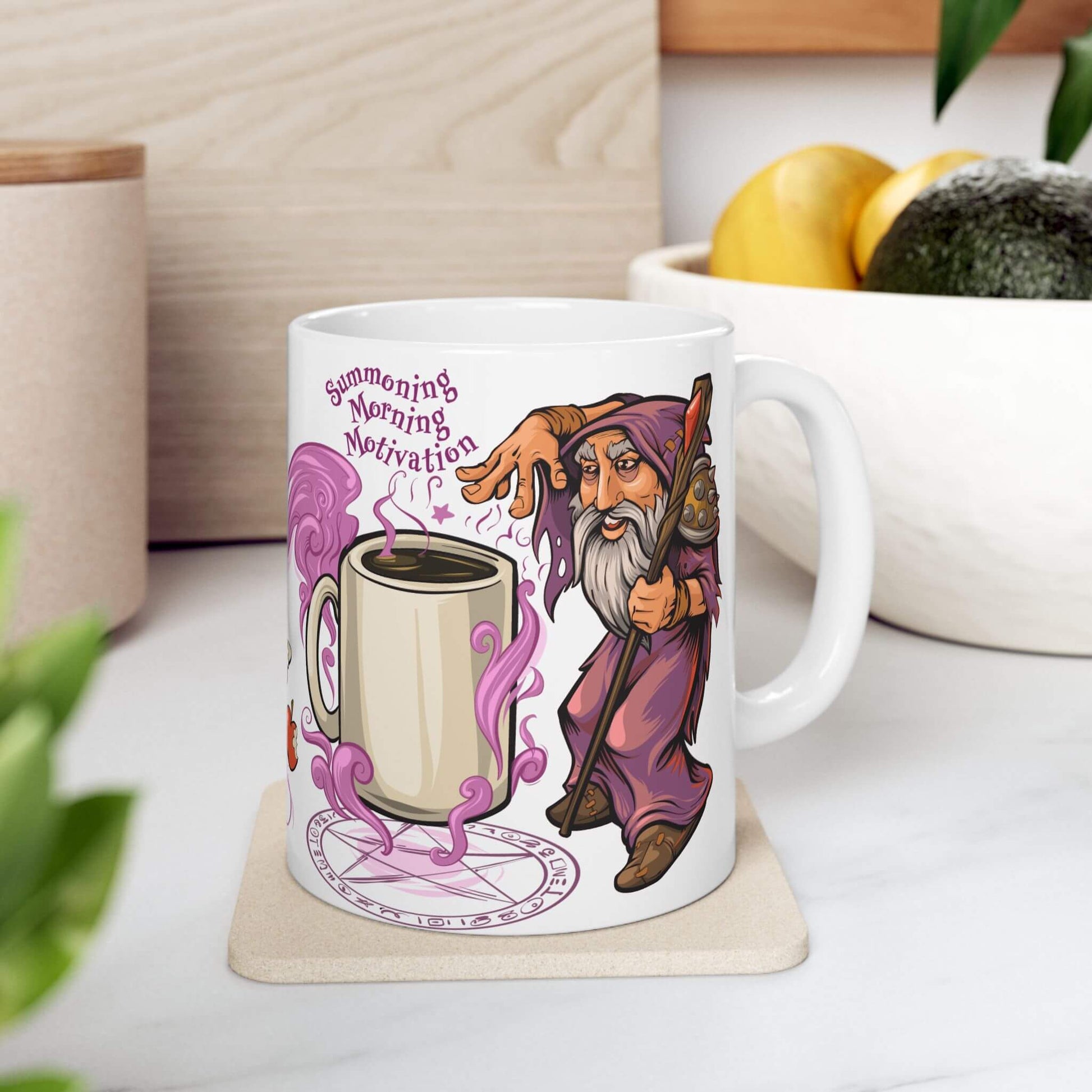 Mug with a cartoon wizard and coffee cup design on a coaster, surrounded by plants and a bowl of fruit.