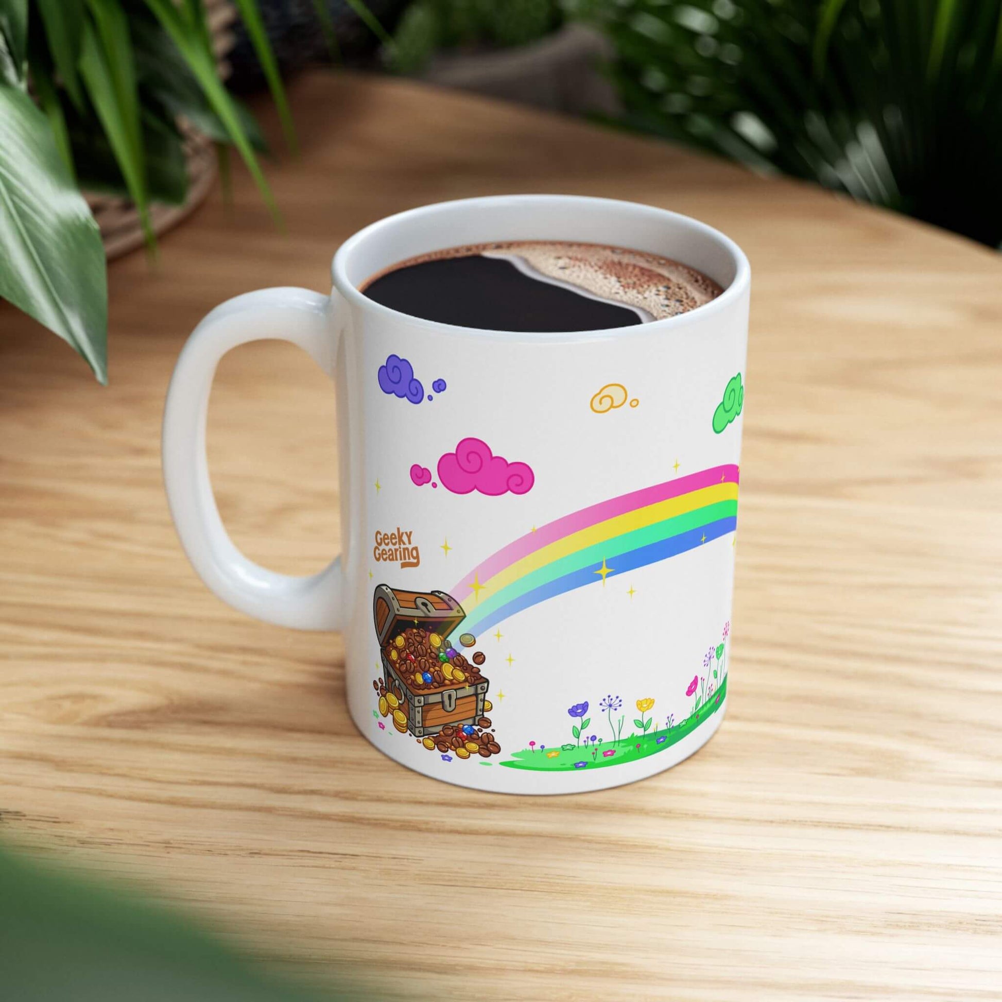 Mug with cartoon design featuring a rainbow and treasure chest on a wooden table.