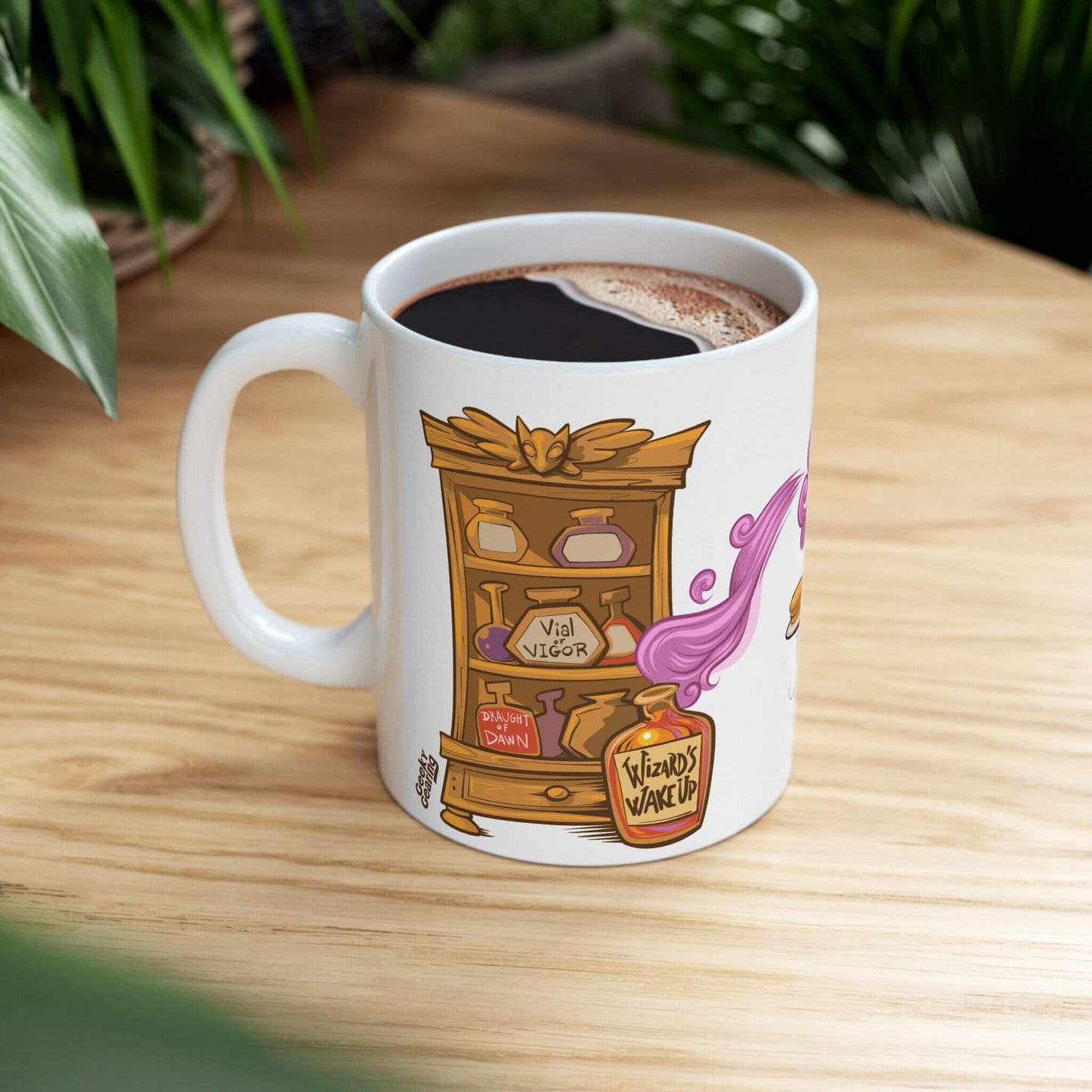 Ceramic mug with cartoon potion cabinet labeled “Vial of Vigor” and “Wizard’s Wake-Up,” filled with coffee on table with plants.