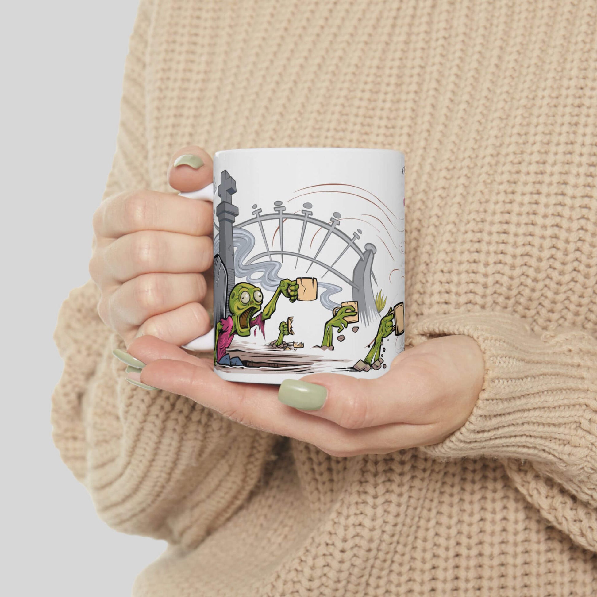 Person holding a mug with a cartoon design of zombies rising from a graveyard