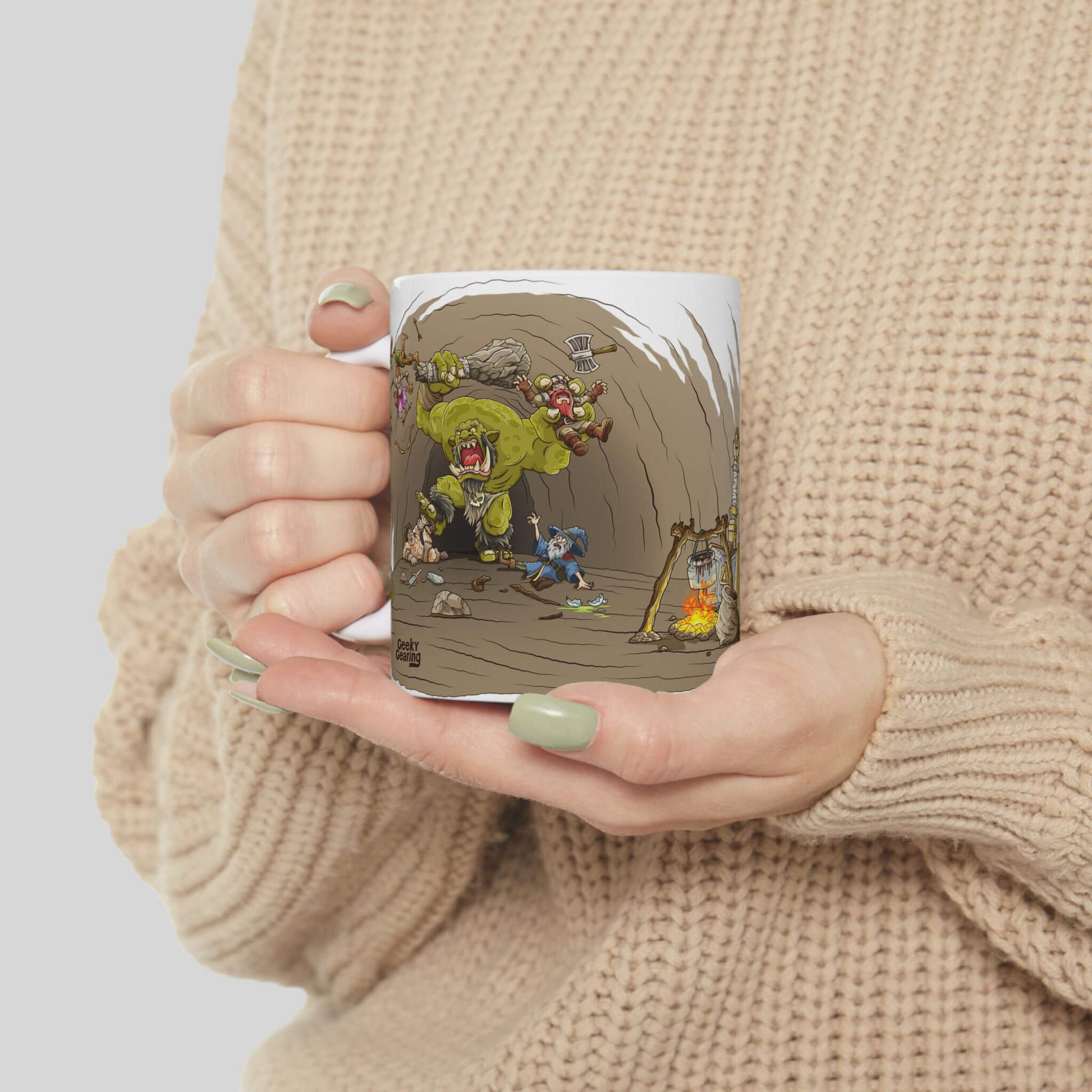 Person holding a mug with a colorful design of a green monster fighting small characters