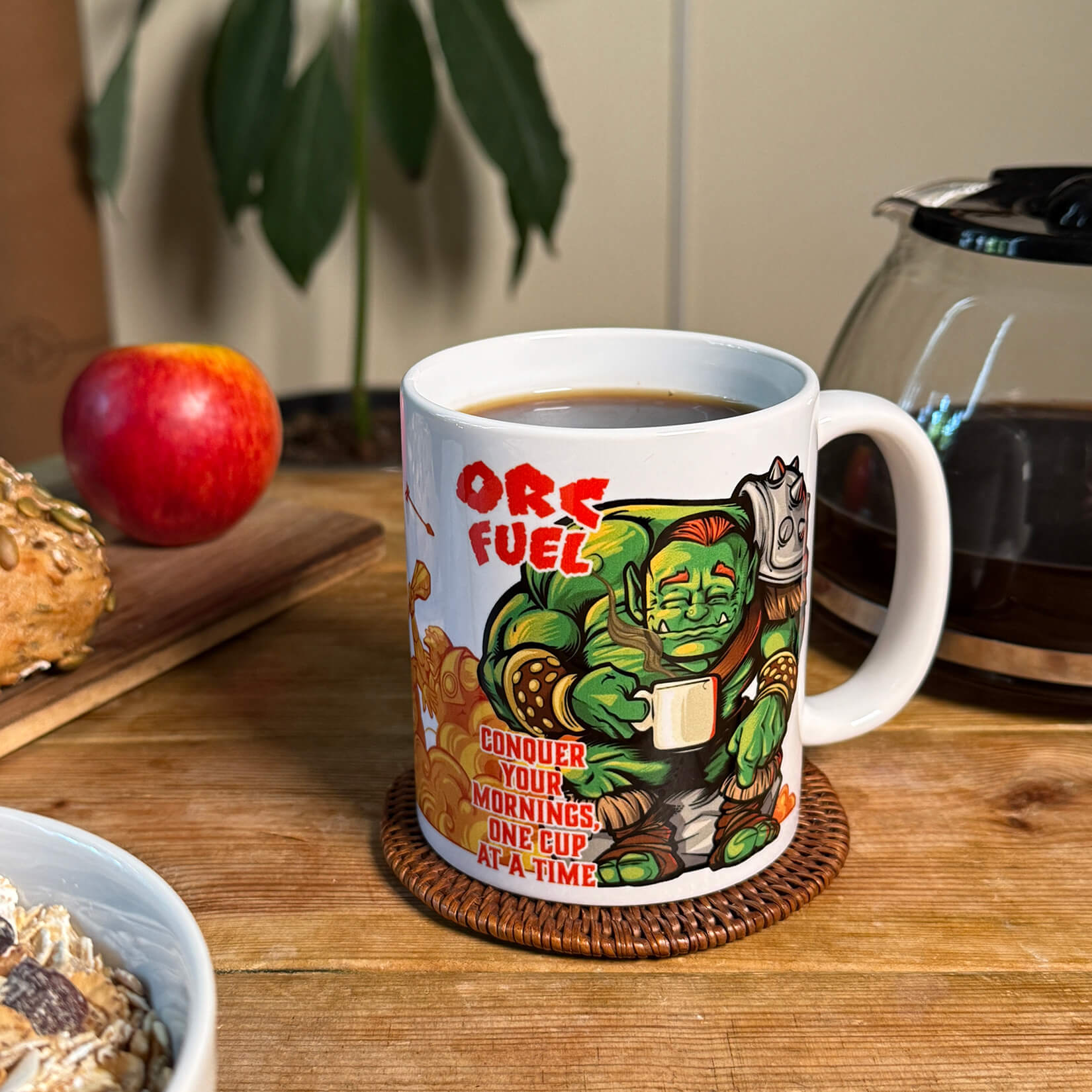 White ceramic fantasy mug with serene cartoon orc drinking coffee; red text: “Conquer your mornings, one cup at a time”
