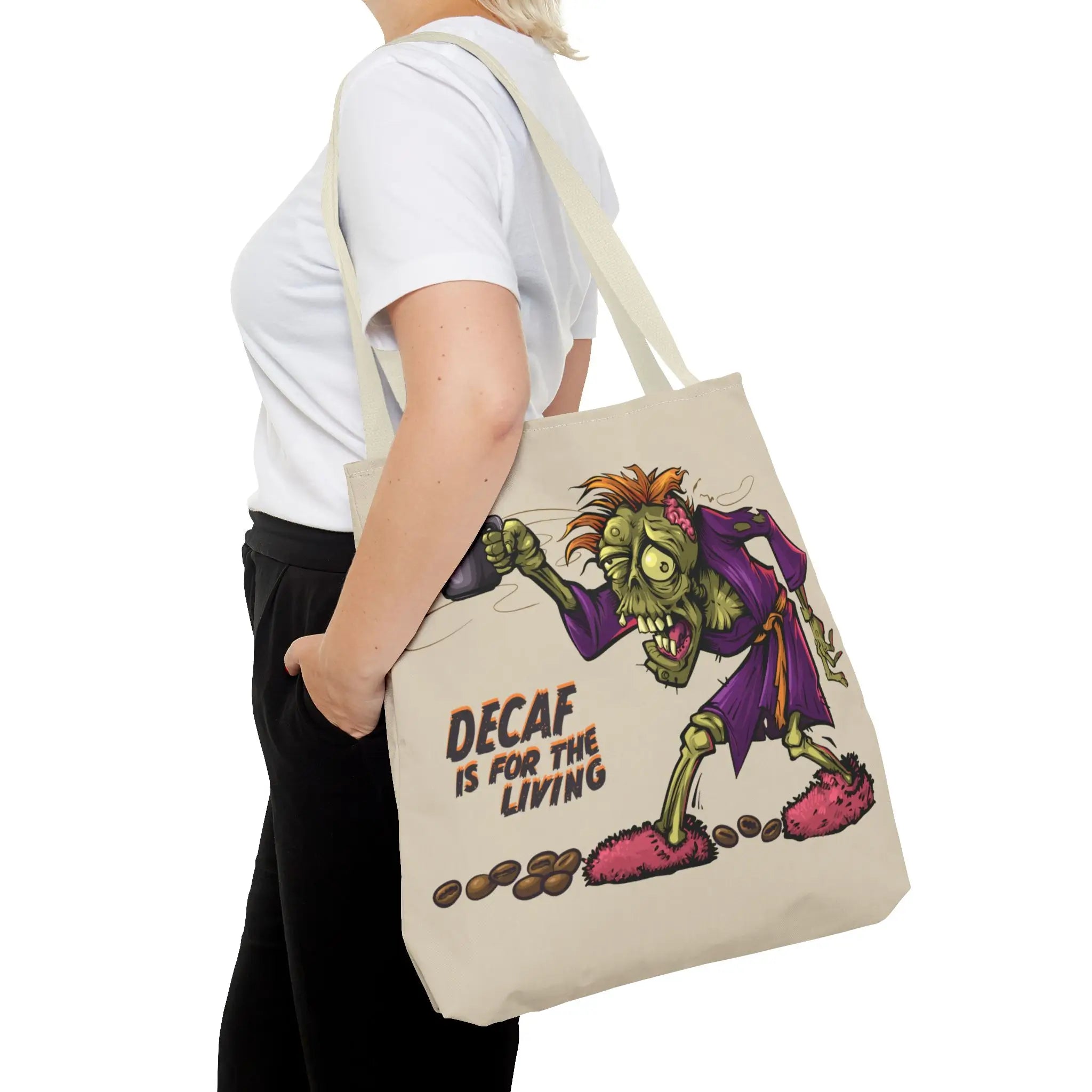 Person holding a tote bag with a cartoon zombie design and text on a white background