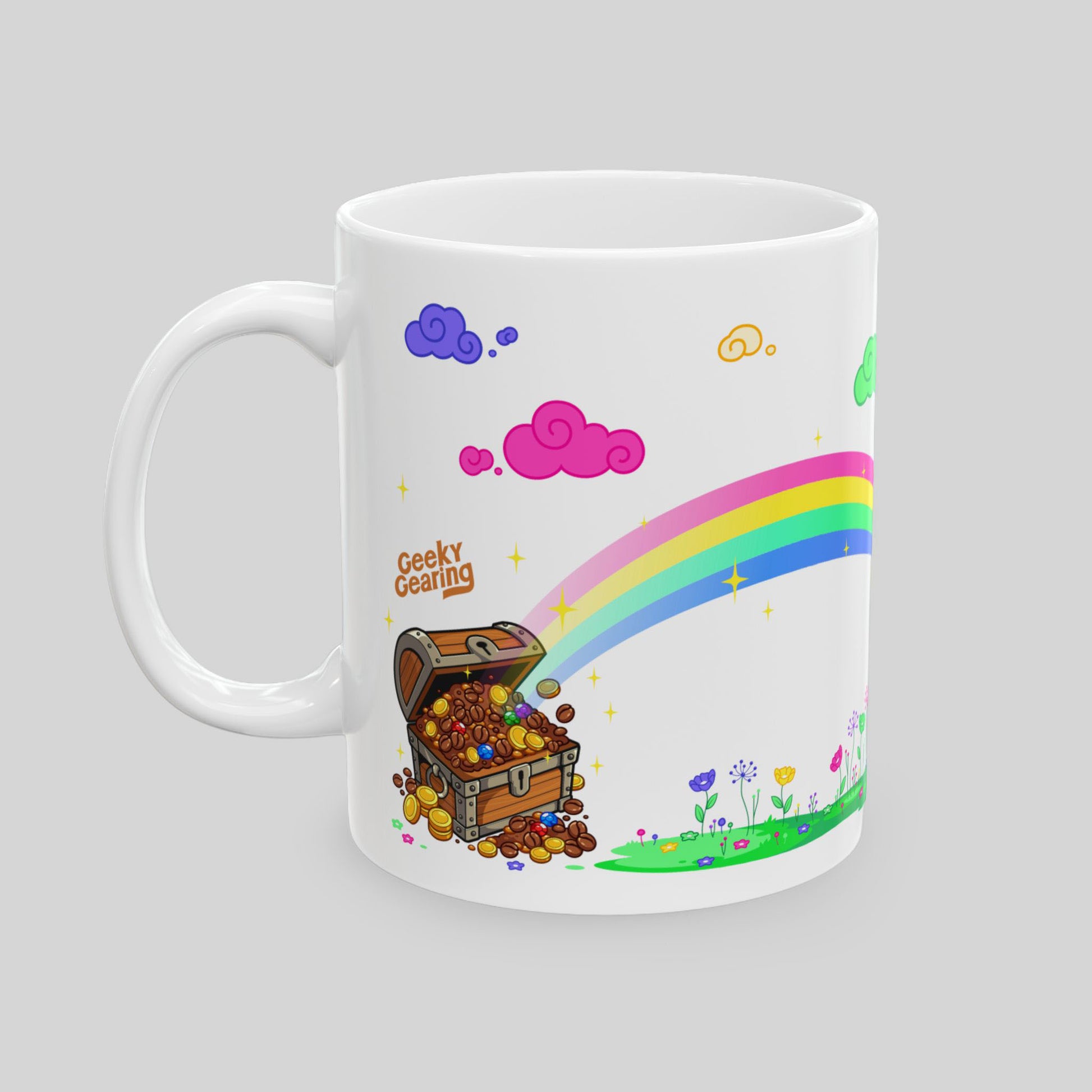 White mug with a colorful design of a treasure chest, rainbow, and clouds on a gray background.