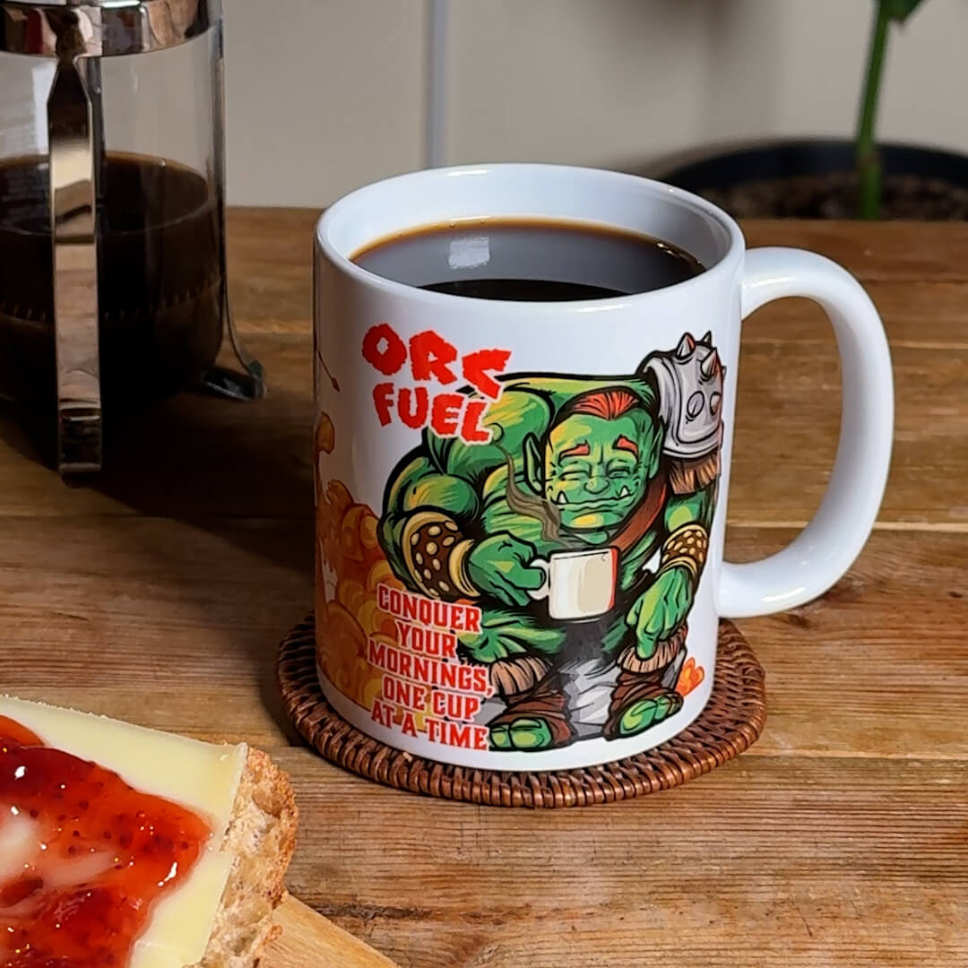 Orc Fuel fantasy coffee mug by GeekyGearing, rotated in hand on breakfast table; French press with coffee behind.
